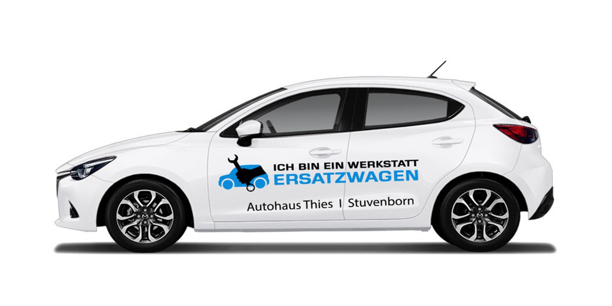 Das Bild zeigt ein weißes Auto mit der Aufschrift: „ICH BIN EIN WERKSTATT ERSATZWAGEN“ sowie „Autohaus Thies | Stuvenborn“. Es ist ein Werkstattersatzwagen.